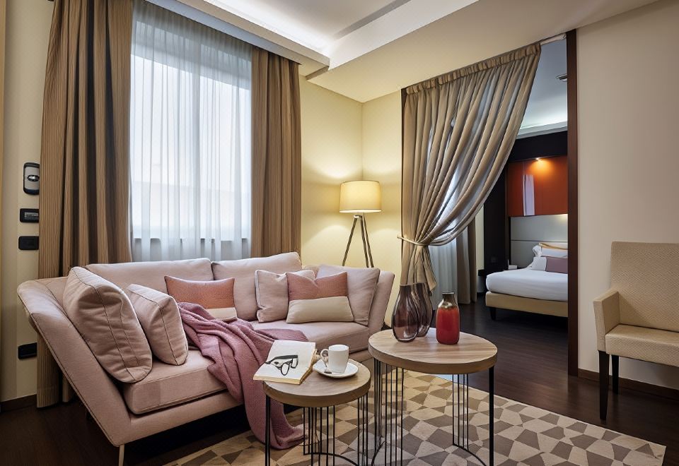 a living room with a couch , coffee table , and lamp is shown next to a bedroom at Winter Garden Hotel Bergamo Airport