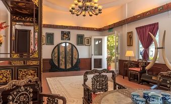 a room with a large circular mirror hanging on the wall , surrounded by ornate furniture and decorations at Shah's Beach Resort Malacca