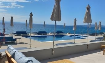 a rooftop patio overlooking the ocean , with several lounge chairs and umbrellas placed around it at Hotel Savoy