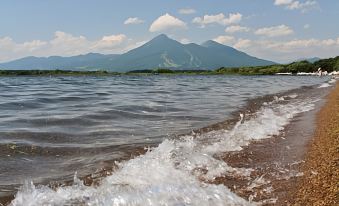 a beach scene with a mountain in the background and water waves lapping against the shore at Moritaya