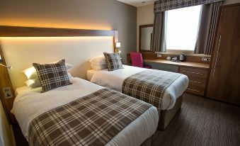 a hotel room with two beds , each made with white sheets and brown plaid bedspreads , next to a window with curtains at Mondo Hotel