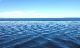 a serene ocean view with clear blue water and a hazy horizon under a partly cloudy sky at Rex Hotel Beppu