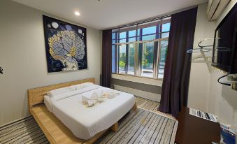 a modern bedroom with a large window , wooden bed , and white bedding , along with a painting on the wall at De' Chukai Hotel