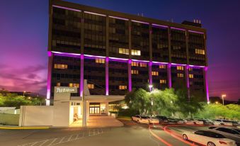 a large building with purple lights illuminating its exterior , and a parking lot outside at night at Hotel NoMa, Trademark Collection by Wyndham