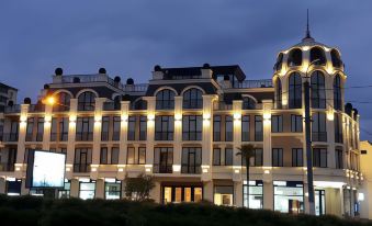 a large building with many windows and balconies is lit up at night , casting a warm glow on the surrounding area at Garden Palace