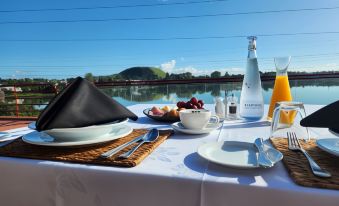 a table is set with a white tablecloth , silverware , and various food items in a room with a view of the water at Waipuna Hotel & Conference Centre