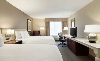 a hotel room with two beds , a desk , and a tv , along with a window and chair at Hilton Garden Inn Gilroy