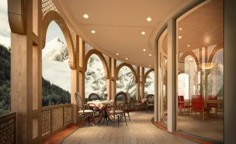 an outdoor dining area with tables and chairs arranged on a patio , overlooking a snow - covered mountain at Pearl Continental Hotel Malam Jabba