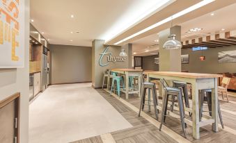 "a modern bar with wooden stools , pendant lights , and a large sign reading "" thyme "" on the wall" at Premier Inn Penzance