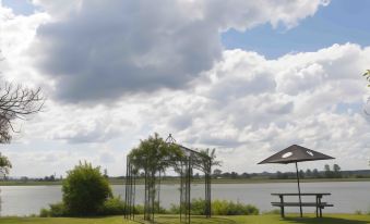 a beautiful landscape with a lake , trees , and a gazebo , under a cloudy sky with scattered clouds at Ulmarra Hotel