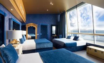 a modern hotel room with blue walls , white ceiling , and two beds with blue bedding , arranged in a spacious layout at Arthouse Hotel