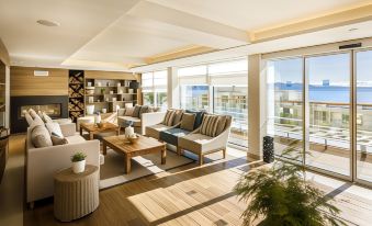 a modern living room with wooden floors , large windows , and multiple couches arranged around a coffee table at Valamar Bellevue Resort