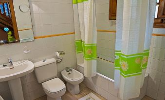 a bathroom with a toilet , sink , and shower curtain is shown next to a window at Viviendas Rurales Traldega