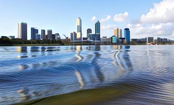 a city skyline reflected in a calm body of water , creating ripples on the surface at Broadwater Resort Como