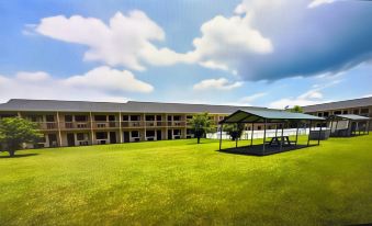 a large building with multiple floors and balconies , surrounded by green grass and a blue sky at Americas Best Value Inn Canton