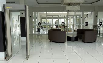 a modern hotel lobby with white tile flooring , black and white furniture , and large windows at Hotel Bonero Residence