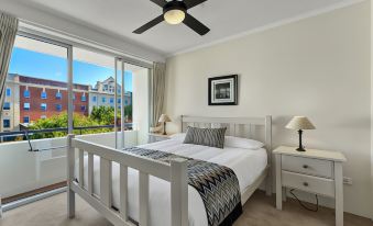 a bedroom with a large bed and white furniture , featuring a ceiling fan and sliding glass doors at Goldsborough Place Apartments