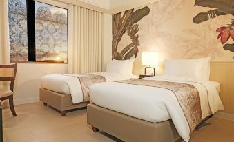 a hotel room with two beds , a painting on the wall , and a lamp on one bed at Brittany Hotel Global South Formerly Mella Hotel