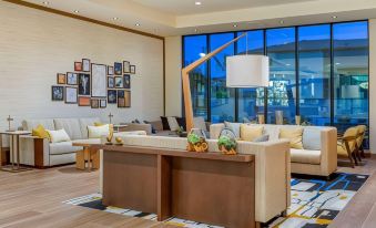 a modern living room with a large window , white couches , and a wooden coffee table at Hotel Centro Sonoma Wine Country, Tapestry by Hilton