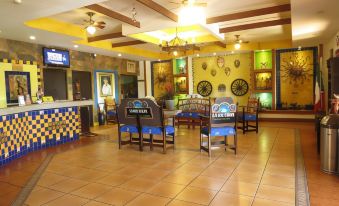 a restaurant with a bar area and dining tables , all decorated in yellow and blue at Hotel La Hacienda