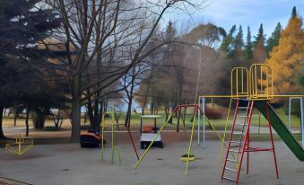 a park with a variety of playground equipment , including swings , slides , and a jungle gym at The Camp - Lake Hawea