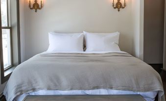 a large bed with white linens and two nightstands are in a room with wooden flooring at Stonehill's Farmhouse
