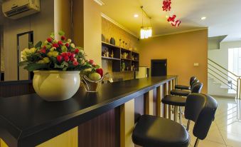 a bar with a wooden counter and black chairs , featuring a vase of flowers and bowls at RedDoorz Plus @ Paal 2 Manado