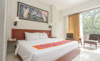a large bed with a white comforter and orange runner in a room with a window and curtains at Ubud Hotel & Cottages