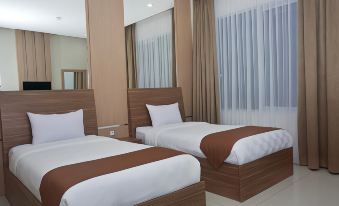 a hotel room with two beds , one on the left and one on the right side of the room at Grand Cordela Hotel As Putra Kuningan