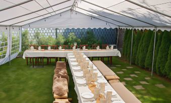 a long dining table set up for a formal event , with white tablecloths and multiple plates on the table at VeLa