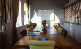 a long wooden table with blue place mats and green chairs is set up in a room with large windows at Ocean View Residence