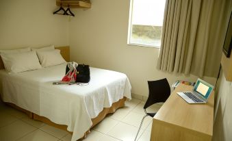 a small hotel room with a bed , desk , and window , decorated in white and black colors at Hotel Capital