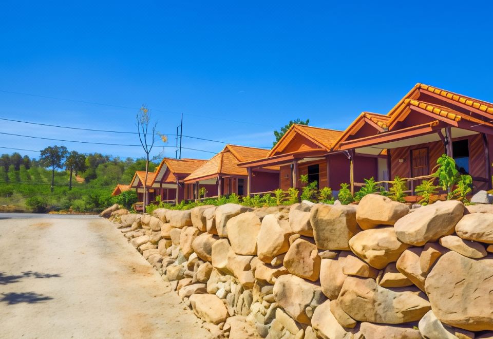 a row of houses with orange roofs are lined up along a stone wall and road at Palmsuay Resort