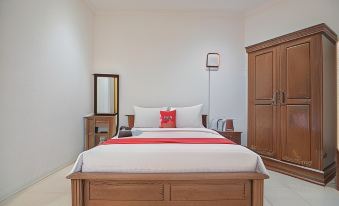 a large bed with a red and white striped blanket is in the center of a room at RedDoorz Near Jatinangor Town Square