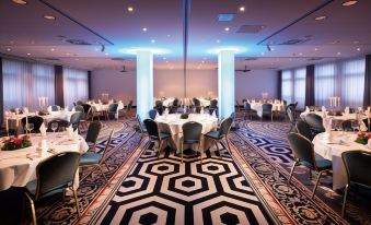 a large dining room with multiple tables and chairs set up for a formal event , possibly a wedding reception at Ginn Hotel Berlin Potsdam