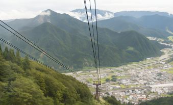 a cable car traveling through a mountainous landscape , with the city of fuzhou visible in the distance at Shosenkaku Kagetsu