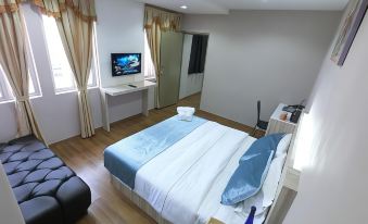 a clean and well - organized hotel room with a comfortable bed , a desk , and a television at Royale Hotel Batu Gajah