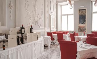 a dining room with white tablecloths on red chairs and tables , as well as wine bottles on display at Hotel de Ville