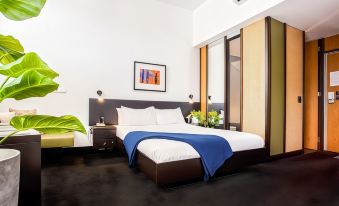 a modern bedroom with white walls , black carpet , and a bed dressed in blue comforter at Middle Park Hotel