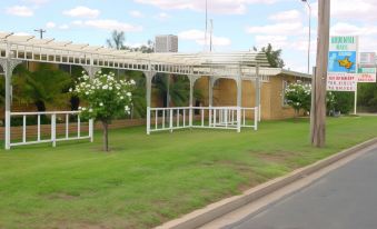 a white gazebo on a grassy field , surrounded by trees and buildings , with a road visible in the background at Ardeanal Motel