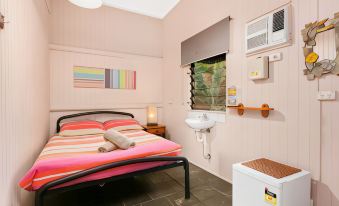 a small , cozy bedroom with a bed , a sink , and various decorations on the walls at Dreamtime Travellers Rest