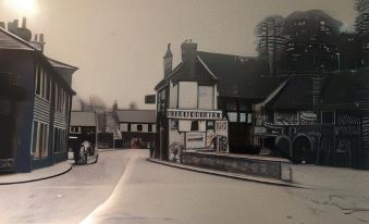 a black and white photograph of a city street with buildings and people in the background at OYO The Greyhound Inn
