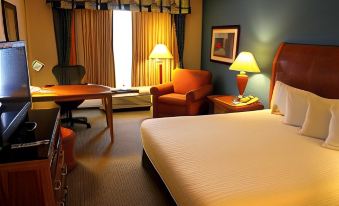 a hotel room with a bed , chairs , and a desk , along with some items on the desk at Hilton Garden Inn Albany