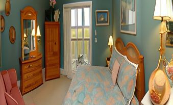 a well - decorated bedroom with a bed , dresser , and chair , as well as a balcony view outside at The Sunset Inn