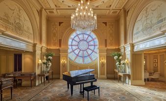 a grand piano is placed in a large , ornate room with a chandelier and potted plants at Four Seasons Hotel Cairo at the First Residence