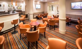a spacious , well - lit restaurant with multiple dining tables and chairs , as well as a bar area at Hotel Saint Georges
