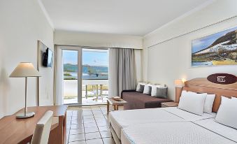 a hotel room with a balcony overlooking the ocean , featuring a bed , couch , and tv at Labranda Blue Bay Resort