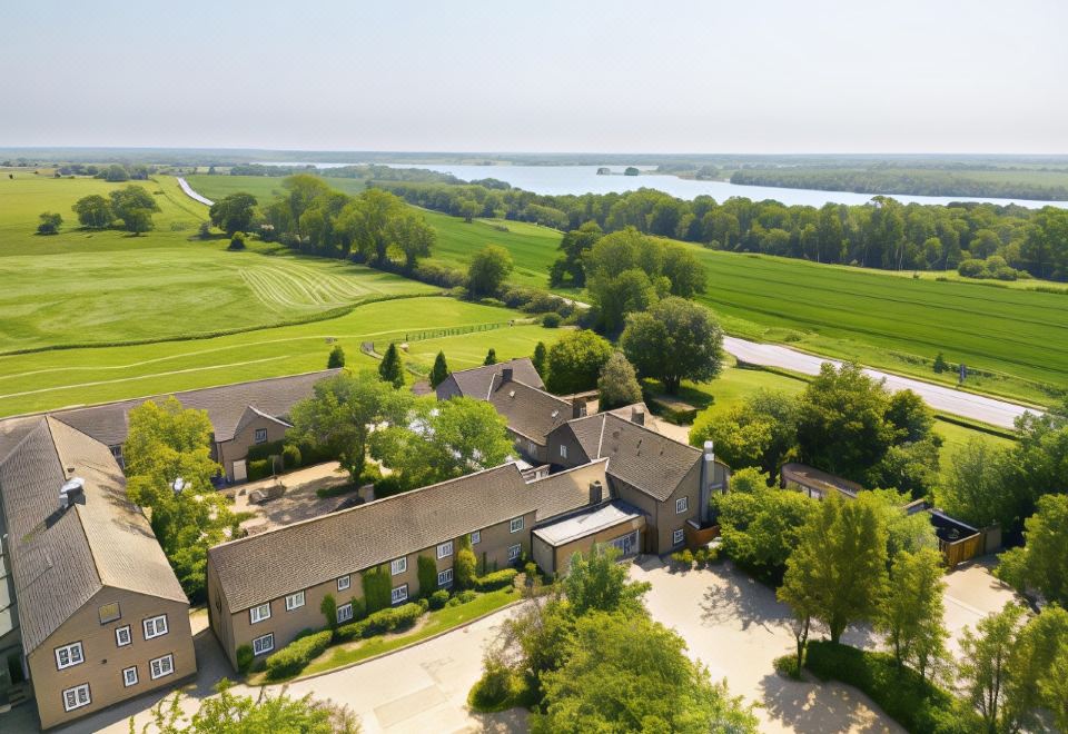 aerial view of a large house surrounded by green fields and a body of water at The Barnsdale, Rutland