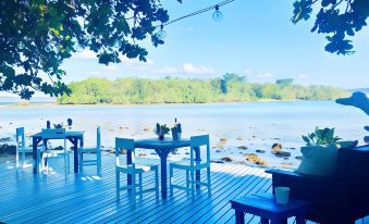 a wooden deck overlooking a body of water , with a dining table and chairs set up for a meal at Turtle Bay Lodge