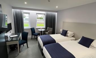 a hotel room with two beds , a desk , and a window , all decorated in a modern style at Dean Park Hotel